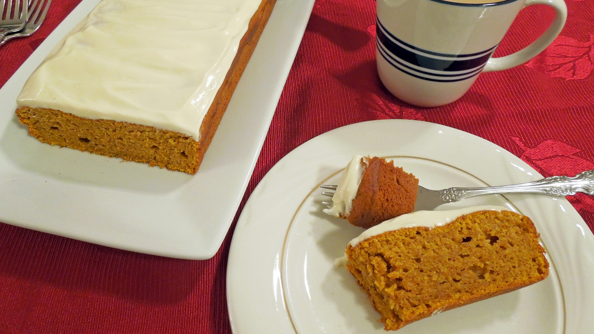 Pictured: Slice of pumpkin bread with cross-section of the loaf displayed, served with a cup of coffee.